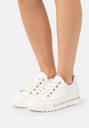 Weiße Ledersneakers mit einer strukturierten Oberfläche, goldenen Ösen und beigen Schnürsenkeln. Dicke weiße Laufsohle mit einem silbernen Akzentstreifen.