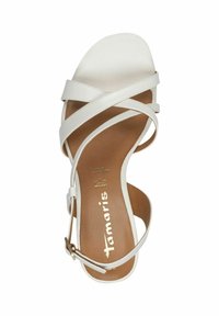 Vit klacksandals med korsade remmar gjorda av slät material, en brun innersula och en guldlogotyp; har ankelrem med spänne.