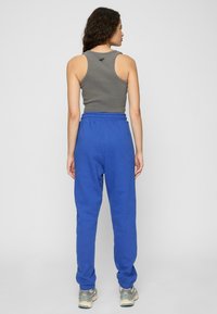 Grå bomullstanktop og blå joggebukser med elastisk liv. Joggebuksene har oppbrettede ankler og en avslappet passform.
