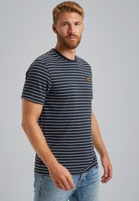 T-shirt à manches courtes rayé bleu marine avec un col rond et un petit patch logo sur la poitrine. Matière en coton doux avec une coupe normale.
