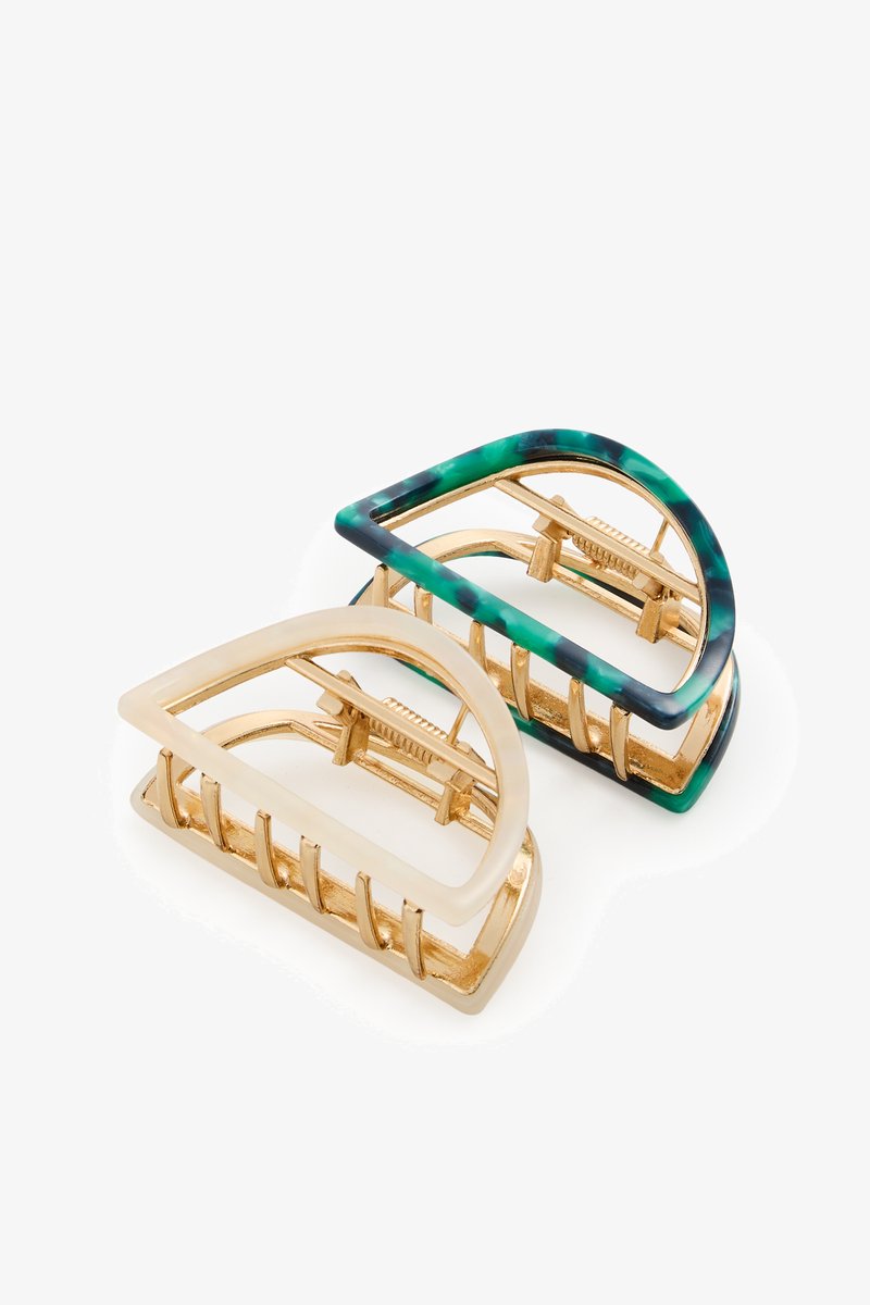 Two geometric half-circle hair clips with gold metal teeth; one clip has green and black marbled edges, the other is cream-colored.