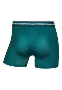 Teal boxer shorts made of smooth fabric, featuring a diamond pattern, an elastic waistband with white branding, and a snug fit.