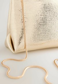 Goldfarbene Metallic-Handtasche mit strukturierter Oberfläche, ausgestattet mit einem geflochtenen Kettenriemen und einem gefalteten Design am Boden.