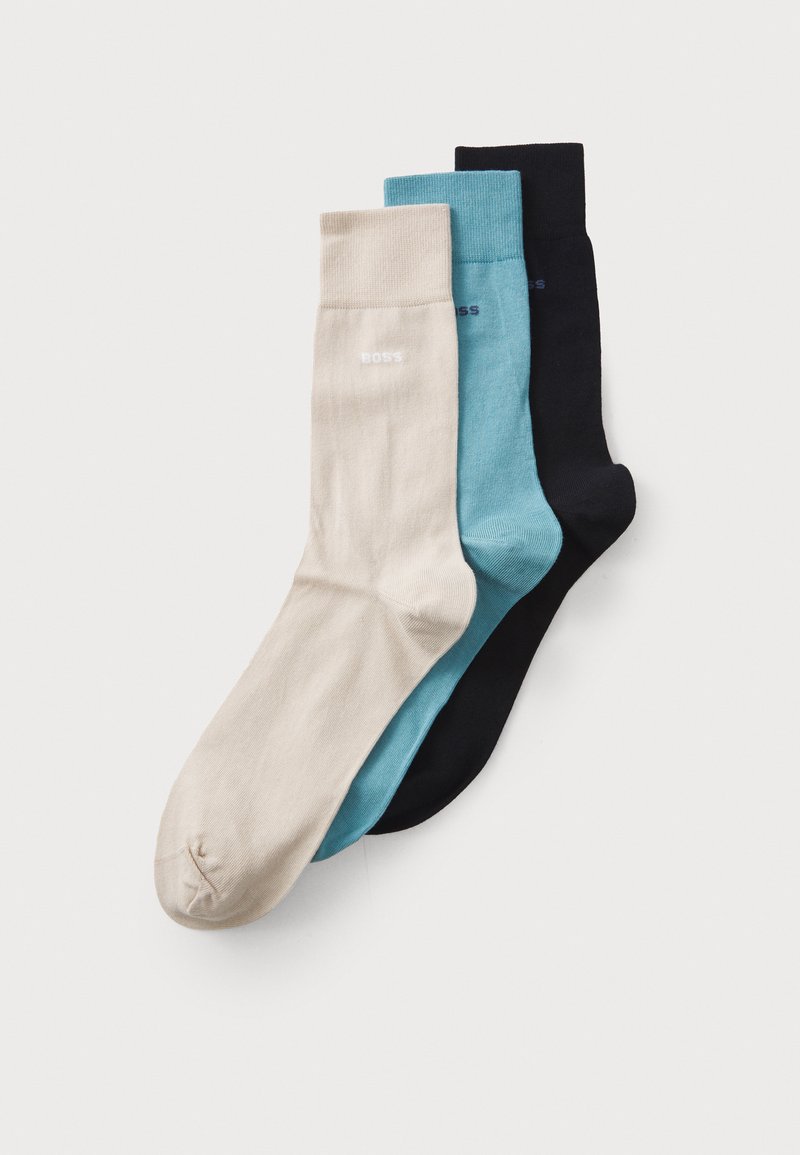 Trois paires de chaussettes de cheville en beige, teal et marine. Fabriquées dans un matériau lisse avec un design simple. Présentent un logo subtil en blanc.