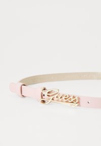 Curea roz din piele, cu o cataramă logo "Guess" aurie, design elegant, cu o textură netedă și curea ajustabilă.