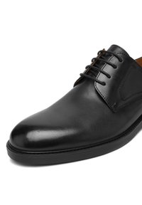 Black polished leather men's dress shoe with closed lacing and rounded toe, shown close-up on a white background.