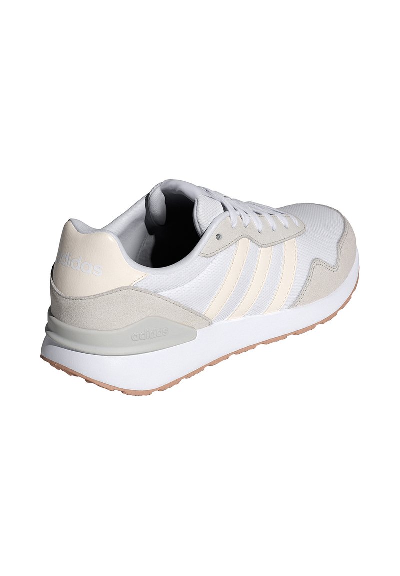 Zapatillas blancas y crema con parte superior de malla texturizada, tres rayas diagonales y suela de goma. Presenta un cuello acolchado y una marca sutil.