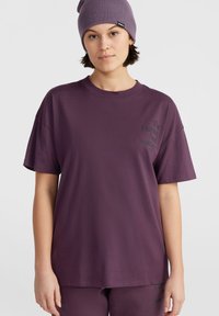 Fialové oversized tričko z bavlny s krátkými rukávy, které má potisk loga na levé části hrudi a kulatý výstřih.