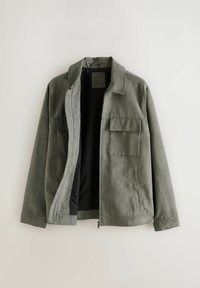 Chaqueta de color verde oliva con cuello, cierre delantero con cremallera, dos bolsillos en el pecho y una textura suave; el interior es negro.