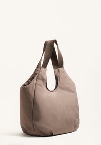 Barna, puha szövet anyagból készült szatyor, ovális kivágású fogantyúval és széles vállpántokkal. Texturált felület és enyhén lekerekített forma.