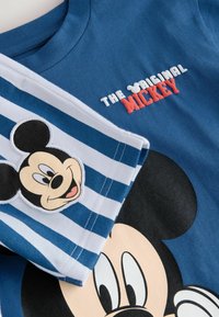 Blå t-shirt med teksten "THE ORIGINAL MICKEY". Har Mickey Mouse grafik, stribet blå og hvid ærme, blødt bomuldsstof.