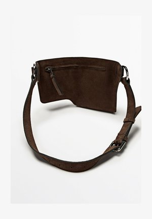 Bruine suède riemtas met een voorvak met rits en verstelbare band met zilverkleurige gesp, afgebeeld op een witte achtergrond.