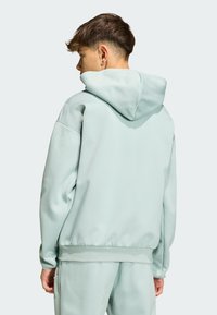 Sudadera con capucha de color verde claro, con cordón en la capucha, dobladillo y puños acanalados. El material parece liso y suave, diseñado para uso casual.