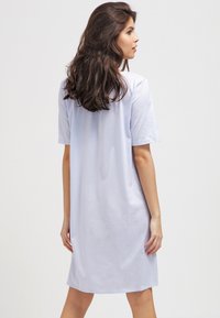 Jasnoniebieska bawełniana sukienka T-shirt z krótkimi rękawami, luźny krój i długość do kolan, wyróżniająca się prostą, gładką teksturą. Gładki wzór bez żadnych motywów.