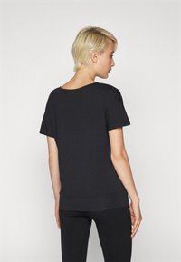 T-shirt nera a maniche corte con vestibilità ampia, scollo rotondo e orlo a coste. Tessuto morbido e design semplice e minimalista.