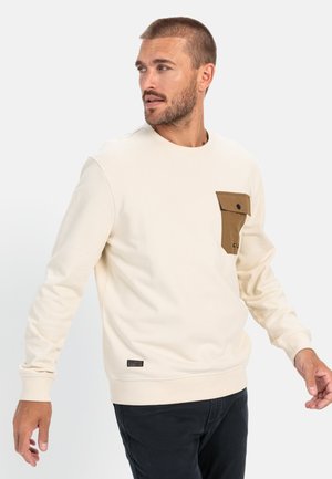 Cream sweatshirt with a brown pocket, crew neckline, and ribbed cuffs. Pocket features a flap and button closure. Tag on lower hem.