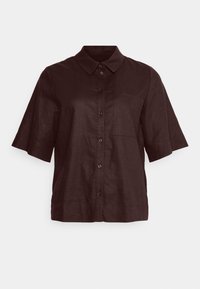 Camisa de linho castanho escuro de manga curta, com gola, fecho de botões e um único bolso no peito. Textura suave e corte descontraído.