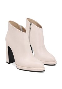 Stivaletti beige alla caviglia con finitura in pelle liscia, punta a punta e tacco alto a blocco. Presentano una cerniera laterale per la chiusura.