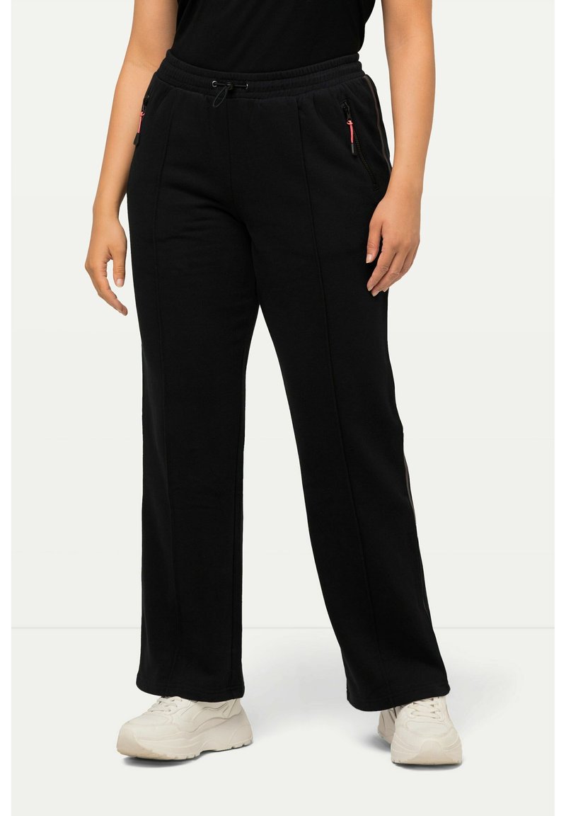 Černé tepláky vyrobené z měkké látky, s pasem na šňůrku a bočními zipovými kapsami s červenými detaily. Fitted design rovného střihu.