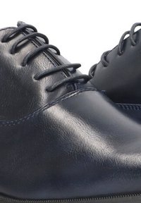 Zapatos de vestir de cuero azul marino con acabado suave, punta redonda, seis ojales para los cordones y suela de goma negra de perfil bajo.