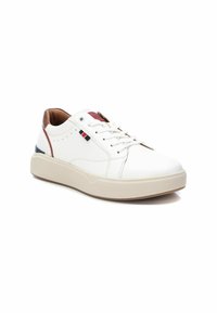 Zapatillas de cuero blancas con un talón marrón, acentos rojos y azul marino, suela gruesa beige y detalles perforados en los laterales. Diseño con cordones.