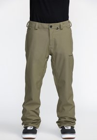 Pantalons de neige vert olive au design droit, avec passants de ceinture, poches avant et un logo de marque discret sur la cuisse. Chaussures noires texturées visibles.
