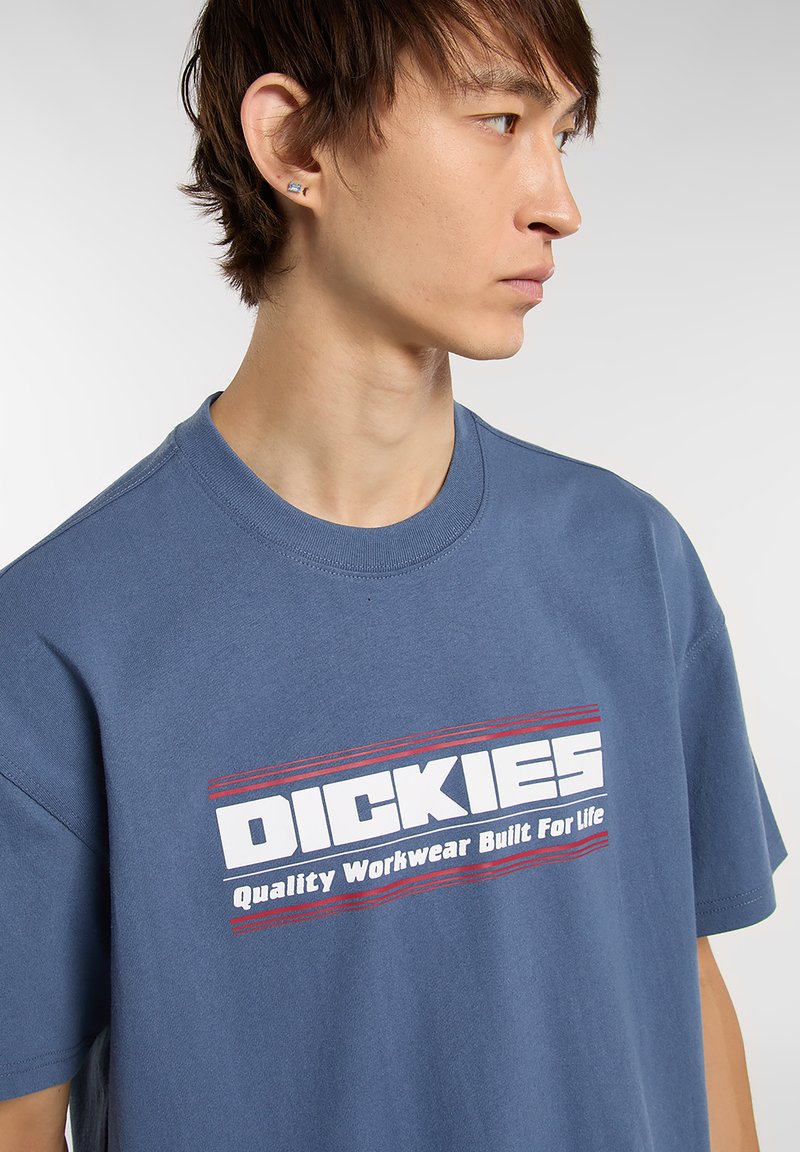 Blue cotton t-shirt features a crew neckline and short sleeves, with a bold white logo and red accents stating "DICKIES Quality Workwear Built For Life."
