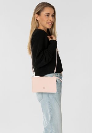 Rosa Leder-Crossbody-Tasche mit schlankem rechteckigem Design, silberner Hardware und einem langen verstellbaren Schultergurt, der an der Hüfte getragen wird.