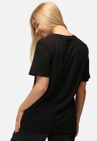Černé tričko s krátkým rukávem vyrobené z měkké bavlny s volným střihem, s kulatým výstřihom a hladkým povrchem. Žádné viditelné vzory ani akcenty.