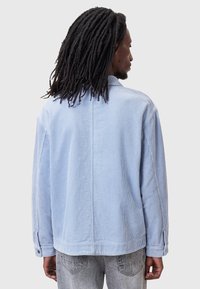 Chaqueta de corte relajado en corduroy azul claro, con un yugo en la parte posterior y mangas largas, detallada con puños abotonados y acanalado vertical.