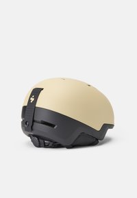 Kask z matowym kremowym górnym elementem i czarną dolną częścią, z regulowanymi paskami, otworami wentylacyjnymi oraz teksturowanym dnem dla lepszej przyczepności.