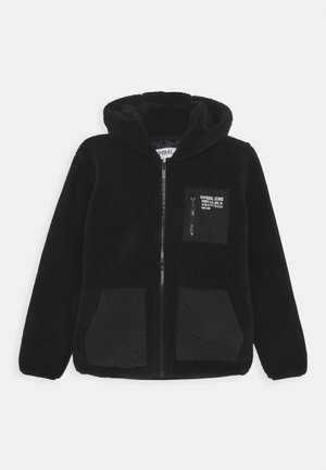 Sudadera con capucha de felpa negra con cremallera frontal, tejido texturizado, dos bolsillos de parche negros y una pequeña etiqueta de logo en el bolsillo del pecho.