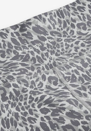 Šedé legíny na cvičení s leopardím vzorem. Mají hladký povrch a viditelné švy podél švů, označené "ACTIVE."