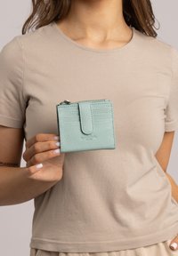 Een gestructureerde lichtgroene leren portemonnee met een drukknoopsluiting, kaartvakjes en een ritsvak. Het heeft een compacte rechthoekige vorm.