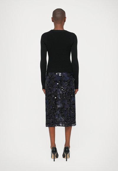 Sweater preto justo com mangas longas, combinado com uma saia azul marinha coberta de lantejoulas, apresentando padrões intrincados e uma textura elegante e suave.