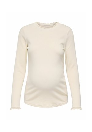 Haut de maternité manches longues couleur crème avec col rond et fine dentelle décorant les poignets et le col, ajusté pour mettre en valeur la forme du ventre.