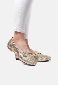 Guldvävda läder loafers med låg klack, prydda med en dekorativ guldfinish på framsidan och slät yta.