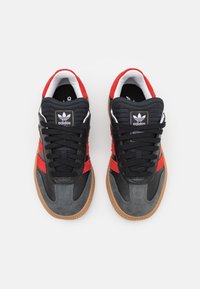 Sorte lær og grå seminær sneakers med røde striper, svarte snører og en gummigummisåle. Klassisk design med polstret krage.