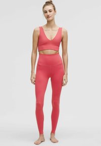 Aangesloten sportkleding in een heldere roze tint, met een cropped top met een V-hals en hoog getailleerde leggings met een gladde textuur.