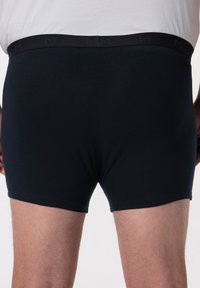 Boxer in cotone nero con design semplice, vita elastica con un logo discreto e vestibilità aderente.