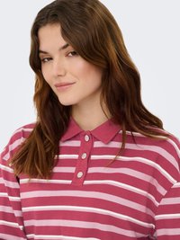 Polo rayé rose et blanc avec un col, comportant trois boutons décoratifs. Tissu en coton lisse avec une coupe décontractée.