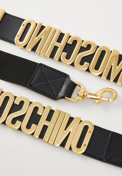 Cintura nera con grande lettering dorato che spell «MOSCHINO», dotata di chiusura a moschettone e texture trapuntata sull'attacco.