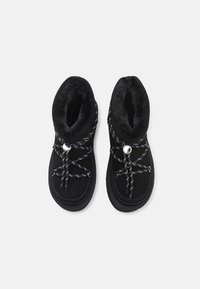 Botas de tobillo negras con un suave forro de piel sintética, material de ante texturizado y cordones en contraste negro y blanco. Detalle de ojal plateado redondo.