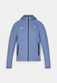 Giacca blu con zip realizzata in tessuto liscio, dotata di cappuccio, tasche con zip nere e logo sul petto. Accentuata con il marchio bianco Nike.