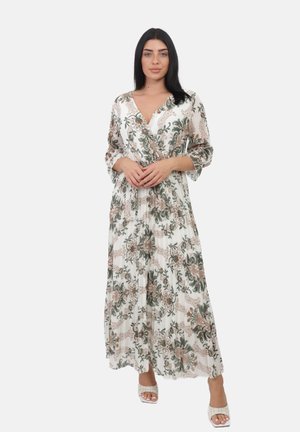 Robe maxi en tissu blanc avec des motifs floraux verts et bruns, décolleté en V, et manches trois-quarts. Assortie à des sandales à talons blanches.