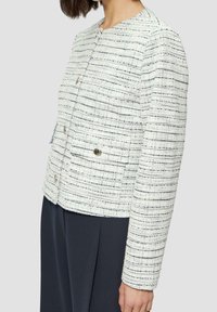 White tweed jacket with horizontal navy stripes, featuring a round neckline, three buttons, and two front pockets. Smooth texture throughout.