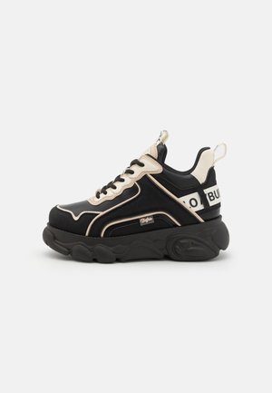 Sneaker-uri masive de culoare neagră cu accente bej, design cu șireturi, talpă căptușită, detalii cu logo și texturi contrastante.