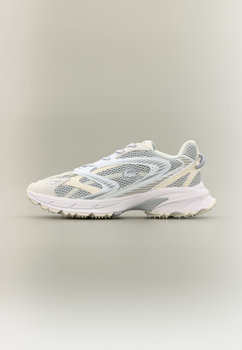 Chaussure de sport gris clair et beige avec dessus en mesh, surpiqûres détaillées, semelle rembourrée et logo discret de la marque sur le côté, vue de profil.