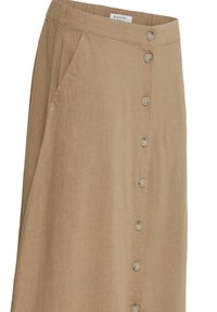 Beige A-line skirt with front buttons, side pockets, and an elastic waistband, made of soft textured fabric.