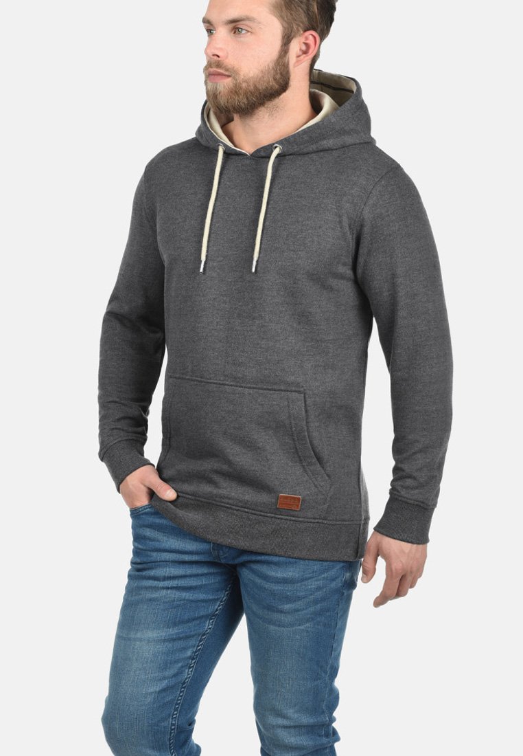 Hematietgrijze hoodie met een buidelzak, beige trekkoorden en een bruin leren patch detail aan de zoom. Zachte, gestructureerde stof.